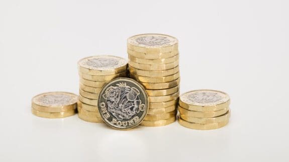 £1 coins stacked on a cream surface