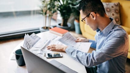 Man using smart phone and laptop for managing finances