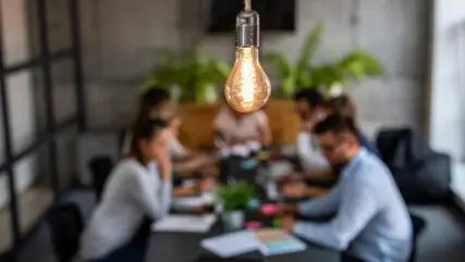 sharp focus lightbulb background blurred image of business people in a meeting looking at EIS advance assurance