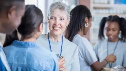 Confident senior female food bank volunteer coordinator instructs a group of volunteers.