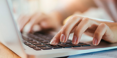 A hand typing on a laptop keyboard.