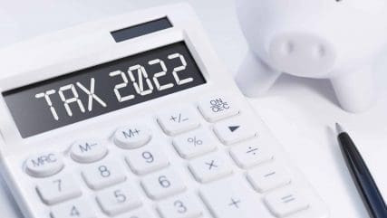 Word Tax 2022 on calculator. Business and tax concept on white background. Top view.