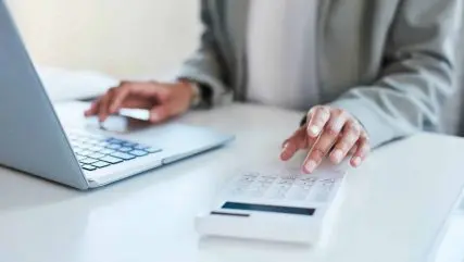 person sitting at desk with laptop and calculator working out National Insurance (NI) changes