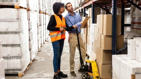 two people in a warehouse with clipboard looking at stock