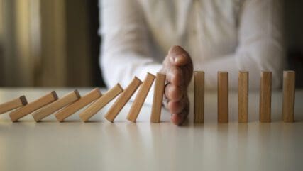 Someone halted their hand to stop the falling dominoes.
