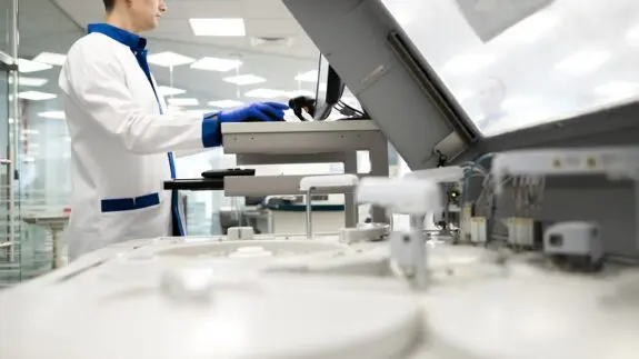 Young man in lab coat doing biochemical blood test in laboratory stock photo