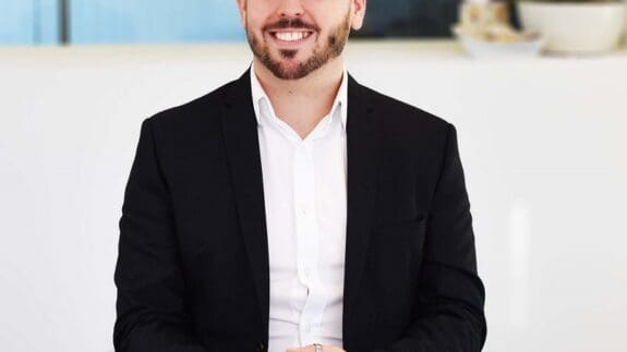 Lee Sharman sitting at desk smiling