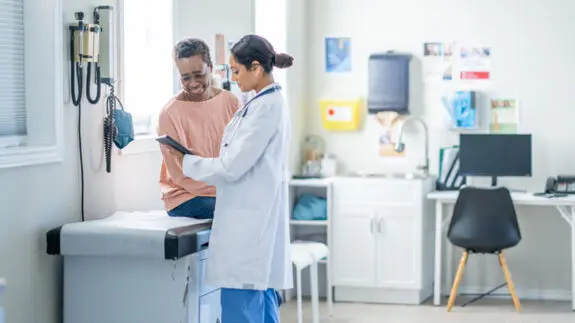Doctor looking at a chart with a patient in a medical room.
