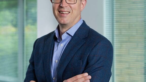 William Wilson standing in office smiling