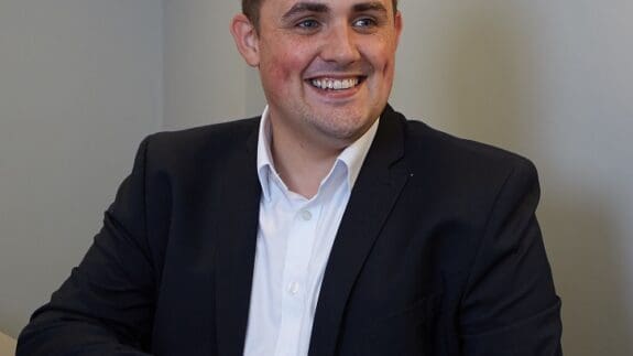 Parry Jackson staff photo sitting at desk smiling
