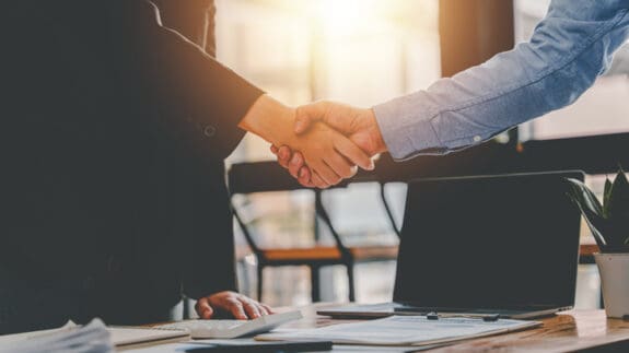 Two people shaking hands across a desk