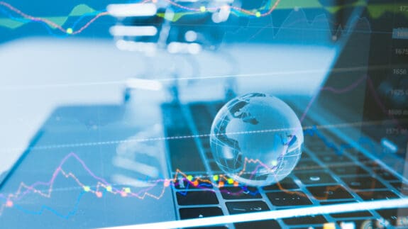 Laptop open with graphic overlay of world and charts