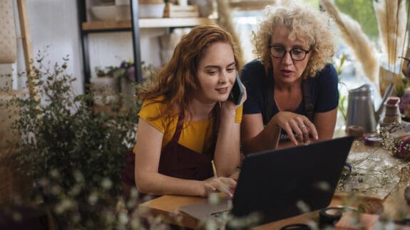 Two women in looking at a laptop screen talking
