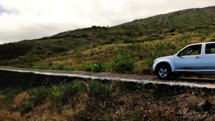 A silver Pickup Truck on a cobblestone road traversing the mountainous volcanic island