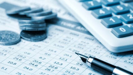 Calculator, coins and pen on finance report
