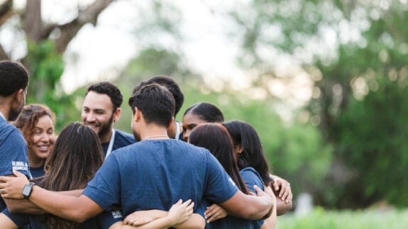 Group of people standing outside in a group hugging