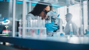 Women scientist in a lab looking through a microscope.