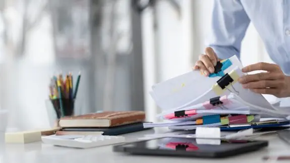 Close up of papers on a desk and person sort through them