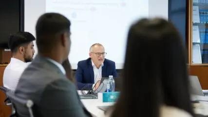 Over the shoulder view of a boardroom with people in a meeting