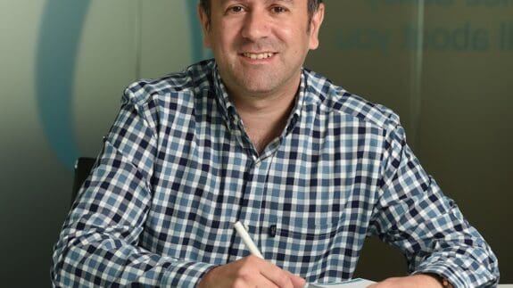 James Elvin sitting at desk smiling at Price Bailey Office, Norwich