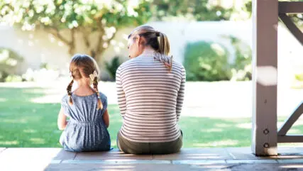 Mother and small child sitting on porch looking out to garden