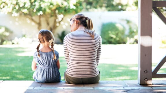 Mother and small child sitting on porch looking out to garden