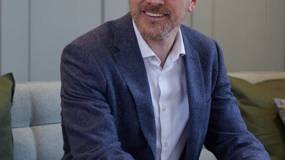 Darren Amott sitting on office sofa smiling