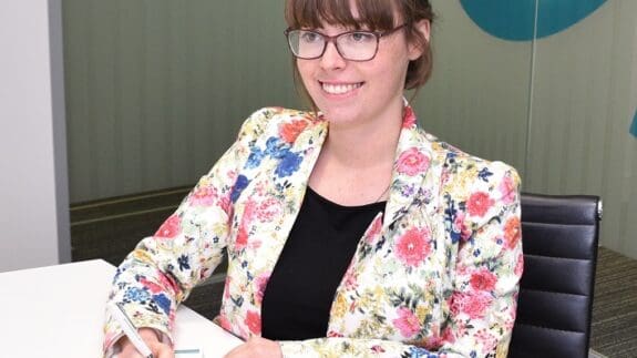 Fiona Jobson sitting at a desk in Cambridge office smiling