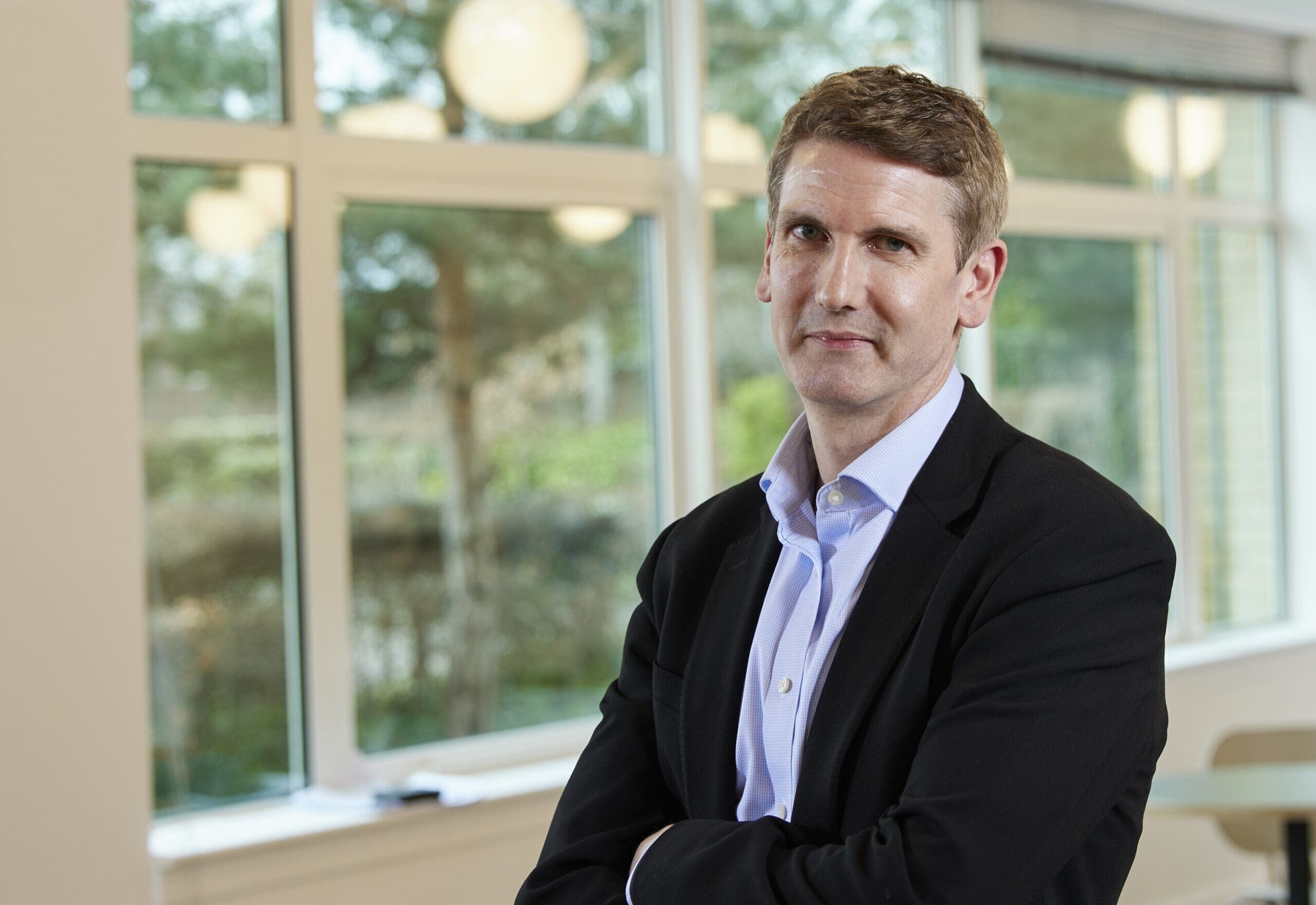 Jon Chambers standing in Cambridge office with arms folded
