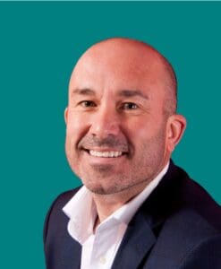 Picture of PB employee Pat Walters with a teal backdrop.