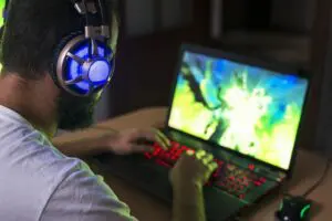 Young gamer playing video games on his laptop, while wearing headphones.