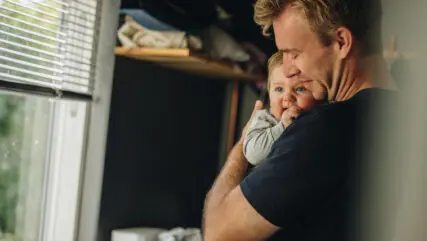 Father consoling his baby. Man holding his baby while standing at home.