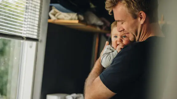 Father consoling his baby. Man holding his baby while standing at home.