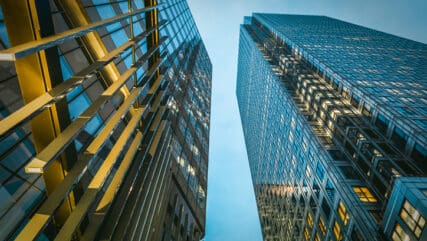skyscrapers towering against a blue evening sky, with illuminated office windows reflecting city lights