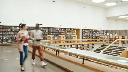 Blurred motion of people walking along the corridor in big library