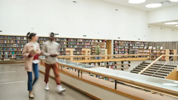 Blurred motion of people walking along the corridor in big library
