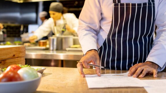 Latin American chef working at a restaurant and looking at the recipes for the menu - food and drink concepts