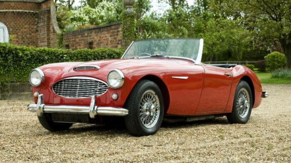 Red Austin-Healey 3000 convertible on gravel driveway, highlighting classic cars as investments