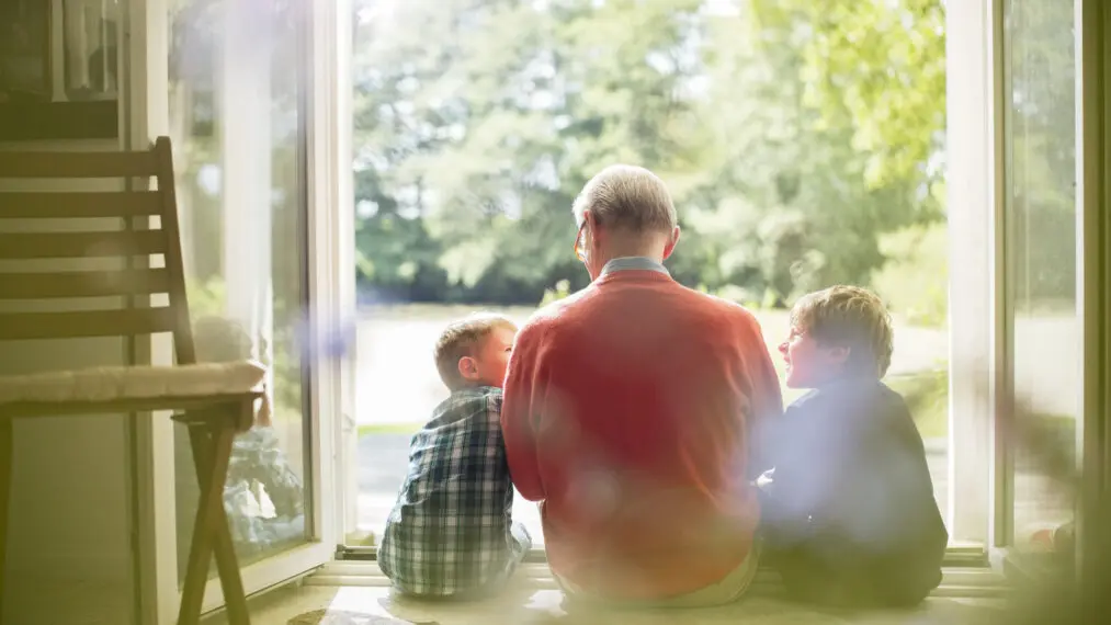 Grandfather and grandsons sitting in doorway