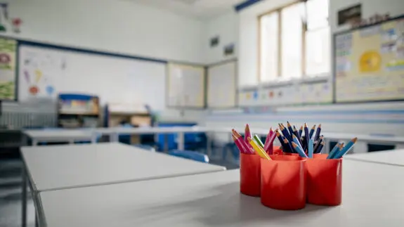 A closeup of an empty classroom with a pot of coloured pencils in red pots. The classroom is in a school in Hexham in the North East of England.