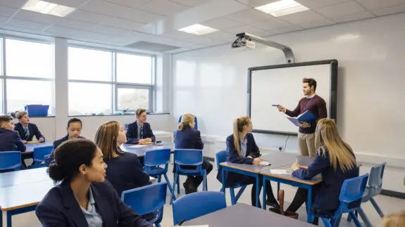 Male teacher is teaching a group of teenagers in a high school lesson.