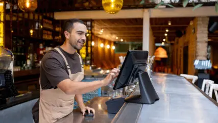 Waiter placing an order on the computer while working at a bar