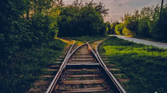A fork in the railroad tracks in two directions. A close-up view of a railroad track. Concept of industrial logistic and transportation background