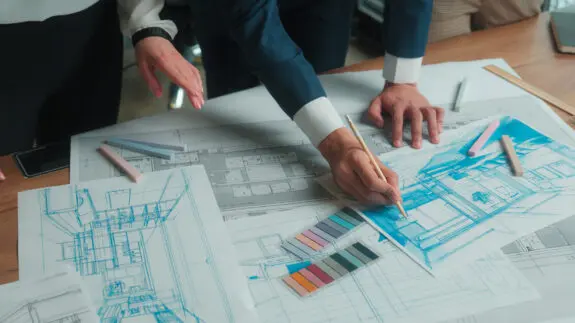 Architecture design project man discusses office interior drawing building floor plan drafting blueprint on paper