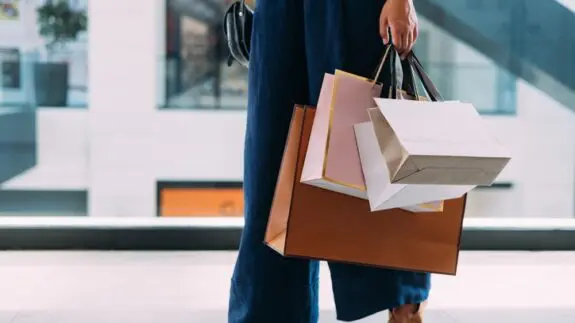 A women standing in the shopping mall with paper bags.