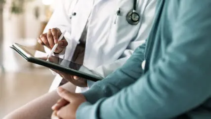 Doctor, hands and tablet with patient for consultation, medical advice or procedure at clinic. Closeup, healthcare employee and client with technology for health appointment or checklist at hospital