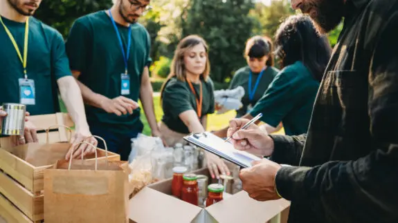 Volunteers are preparing donation boxes at the food and clothes bank. Humanitarian aid project concept.