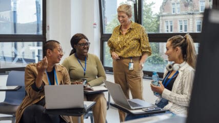 Group of students in a classroom a female teacher is supervising the students.