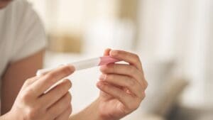 A woman holding a pregnancy test, waiting for the result.