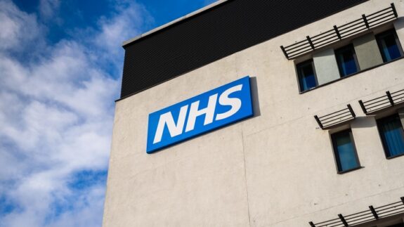 A picture of the outside of a NHS building with the blue NHS sign in focus.